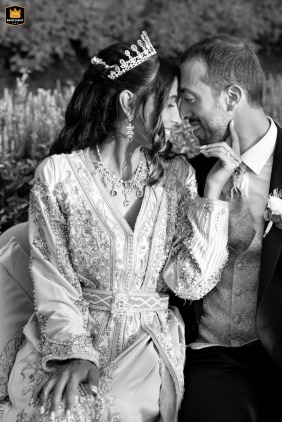 At Casa Celincordia in Cesena, Italy, the bride and groom, dressed in traditional attire, sit face to face in a candid black-and-white shot that captures the tender intimacy and quiet connection between them.